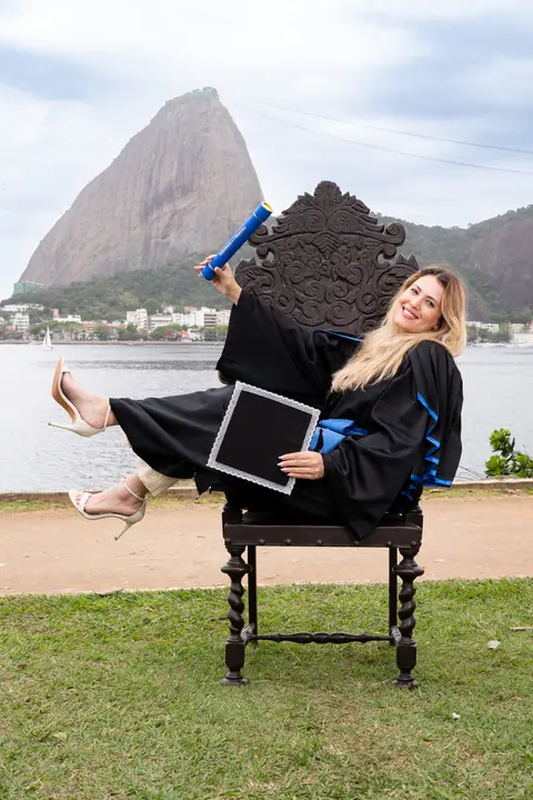 Formanda sentada na cadeira imperial com o diploma na mão